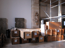 Kisten, in denen bereits Pfeifen verpackt sind. Im Hintergrund die Statue des Heiligen Josef.